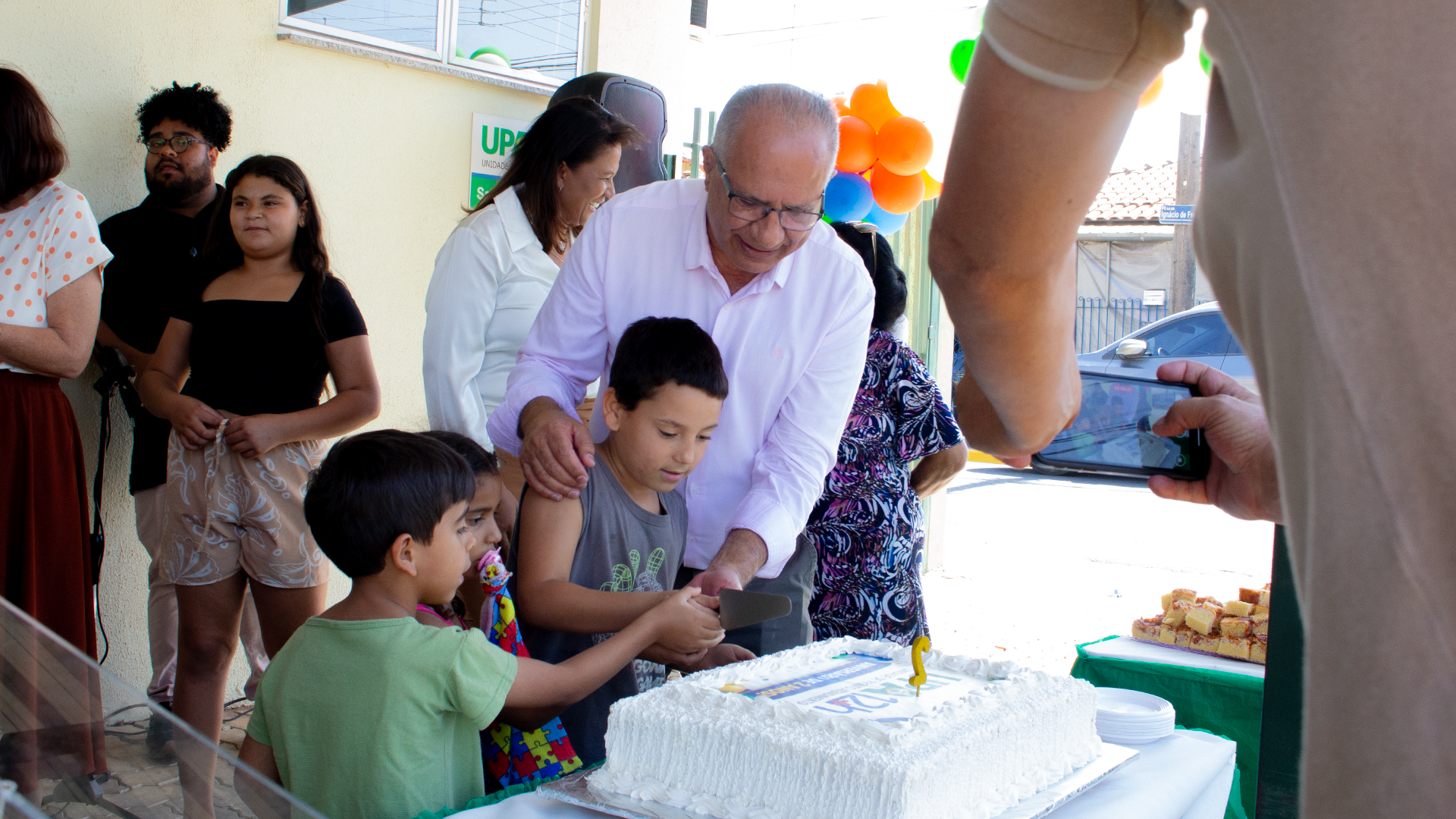 Prefeito Marcelo Simão e crianças presentes fazem o corte cerimonial do bolo de aniversário